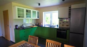 a kitchen with green cabinets and a table and chairs at Vormsi Suvila in Hullo +21 photos