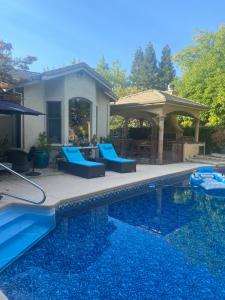 una piscina con sillas azules y un cenador en Tuscany Dorado Resort en Cameron Park