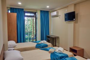 ein Hotelzimmer mit 2 Betten und einem TV in der Unterkunft Villa Story Hotel in Shekhvetili