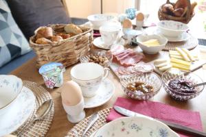 einen Tisch mit Teller und Schalen mit Lebensmitteln in der Unterkunft Manoir du Taillis in Heugon