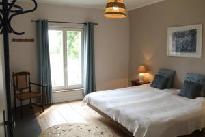 - une chambre avec un grand lit blanc et une fenêtre dans l'établissement Manoir du Taillis, à Heugon