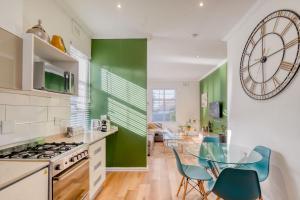 uma cozinha com uma mesa de vidro e paredes verdes em Hampton Collection - Stylish 3 Sleeper Apartment with Pool em Durban