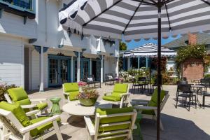 a patio with chairs and tables and an umbrella at Mill Rose Inn in Half Moon Bay