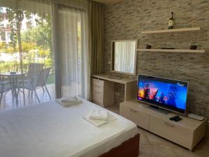 a bedroom with a bed with a television and a table at Sozopol studio deluxe Green life resort in Sozopol