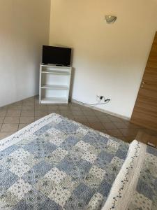 1 dormitorio con 1 cama y TV en la pared en Il Vecchio Casale, en Porto Azzurro