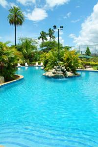 a large swimming pool in a resort with palm trees at Grand West Villas in Nadi