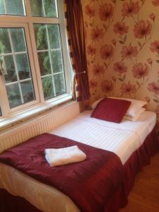 a bed in a room with two windows at The Bridge House in Hounslow