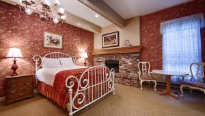 1 dormitorio con cama blanca y chimenea en Best Western Grandma's Feather Bed, en Mendenhaven