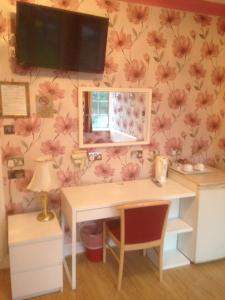 a desk with a television on a wall with flowers at The Bridge House in Hounslow