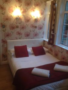 a bedroom with a large white bed with red pillows at The Bridge House in Hounslow