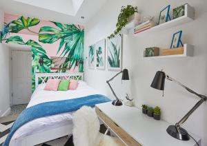 sypialnia z białym łóżkiem i biurkiem z niebieskim kocem w obiekcie The Flamingo w Londynie
