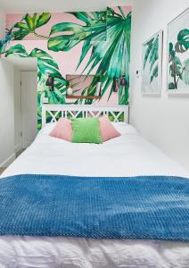 a bedroom with a large white bed with a tropical wallpaper at The Flamingo in London