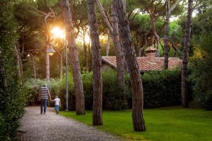 um homem e uma criança a caminhar por um caminho num parque em Villaggio I Sorbizzi em Marina di Bibbona