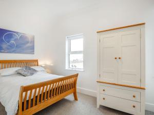スランディドノにあるLittle Orme Viewのベッドルーム1室(木製ベッド1台、白いキャビネット付)