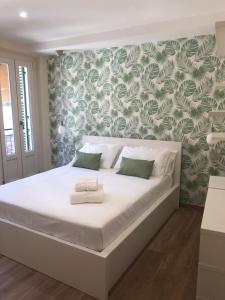 een slaapkamer met een wit bed met groen en wit behang bij Casa Corona Grossa in Saluzzo