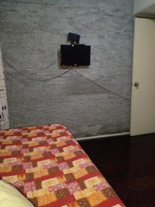 1 dormitorio con 1 cama y TV en una pared de ladrillo en Aurora familiar, en Montevideo