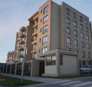 um edifício alto com um carro estacionado em frente em Departamento hermoso, 2 Dormitorios, 2 Baños con piscina, quincho y áreas verdes em Los Ángeles