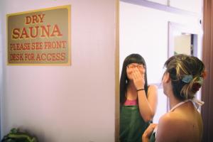 a woman standing in front of a mirror brushing her teeth at Green Tortoise Hostel in San Francisco