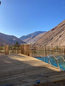 uma ponte de madeira sobre uma piscina de água com montanhas ao fundo em Casa Almendro em Monte Grande