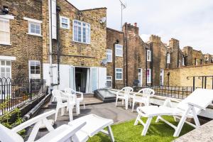 - une rangée de chaises blanches sur une terrasse en face d'un bâtiment dans l'établissement Verv Islington, à Londres