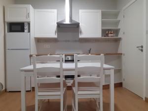 een keuken met witte kasten en een witte tafel en stoelen bij LOFT FRIOL in Friol