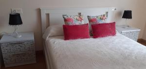 een slaapkamer met een wit bed met rode kussens bij LOFT FRIOL in Friol
