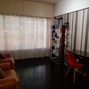 ein Wohnzimmer mit einem Schreibtisch und einem roten Stuhl in der Unterkunft Aurora familiar in Montevideo