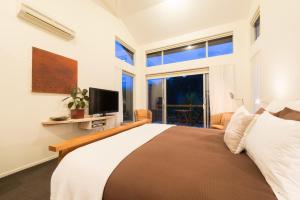 a bedroom with a bed with a television and a window at Stone Store Lodge in Kerikeri