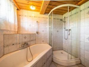 een badkamer met een bad en een glazen douche bij EAGGA-Niederleger Alm in Alpbach