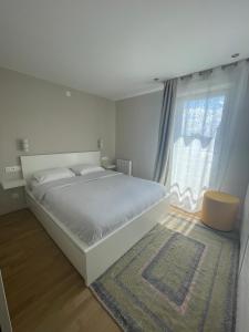a white bedroom with a large bed and a window at Charmant logement aux portes de Paris - STADE DE FRANCE - 12 min à pied in Saint-Denis