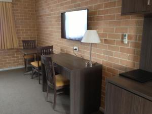 a room with a table and a tv on a brick wall at Alexander The Great Motel in Windsor