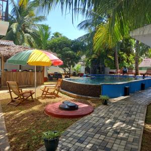 - Piscina con sombrilla, sillas y mesa en Parallel villa en Trincomalee