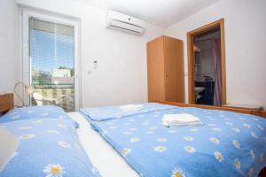 a bedroom with two beds with blue sheets and a window at Apartments with parking space Makarska - 6729 in Makarska