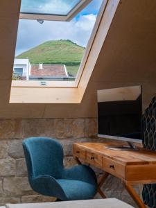 a room with a chair and a desk with a television at Azor Eco Lodge in São Vicente Ferreira