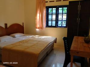 a bedroom with a bed and a table and a window at THE COTTAGE LANGKAWI in Pantai Cenang