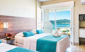 a hotel room with two beds and two windows at Palace Praia Hotel in Florianópolis