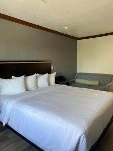 a bedroom with a large white bed and a chair at Starlight Inn Huntington Beach in Huntington Beach