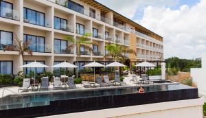 a hotel with a pool and chairs and umbrellas at Hive Cancun by G Hotels in Canc&uacute;n