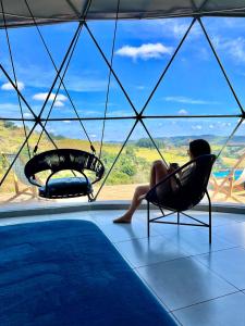 eine Frau auf einem Stuhl neben einem Pool in der Unterkunft Domo geodésico_conforto e relaxamento na natureza in Socorro