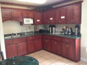 uma cozinha com armários de madeira vermelha e um lavatório em Country Hearth Inn & Suites Augusta em Augusta