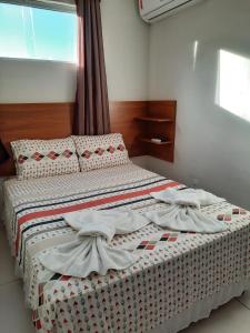 a bedroom with a bed with white sheets and a window at Pousada Avenida in Teixeira de Freitas