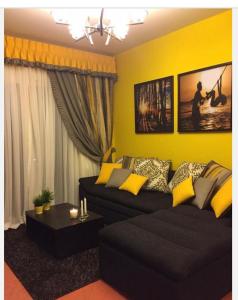 a living room with a black couch and a yellow wall at Golf Porto marina in El Alamein