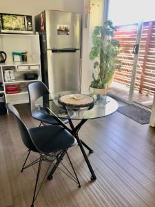 a glass table and chairs in a kitchen with a refrigerator at Brunswick Heads Treetop Studio in Brunswick Heads