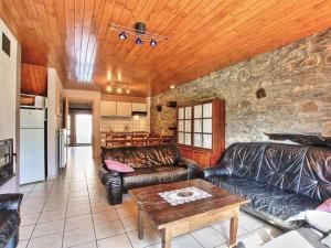 sala de estar con muebles de cuero y pared de piedra. en Rustic holiday home in Sainte-Ode with garden, en Sainte-Ode