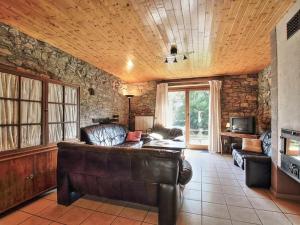 sala de estar con sofá de cuero y pared de piedra en Rustic holiday home in Sainte-Ode with garden, en Sainte-Ode