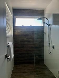 La salle de bains est pourvue d'une douche avec une porte en verre. dans l'établissement Brunswick Heads Treetop Studio, à Brunswick Heads