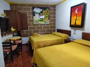 a room with three beds with yellow sheets at Temazcal Hospedaje "gema" adults only in Tepoztlán