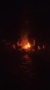 une personne assise autour d'un feu dans l'eau la nuit dans l'établissement Terras de Maria Bonita, à Parati