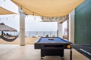 um quarto com uma mesa de bilhar e uma rede de descanso e a praia em Triton's Playhouse Beachfront em Primo Tapia