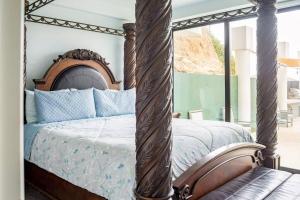a bedroom with a canopy bed with blue pillows at Triton's Playhouse Beachfront in Primo Tapia
